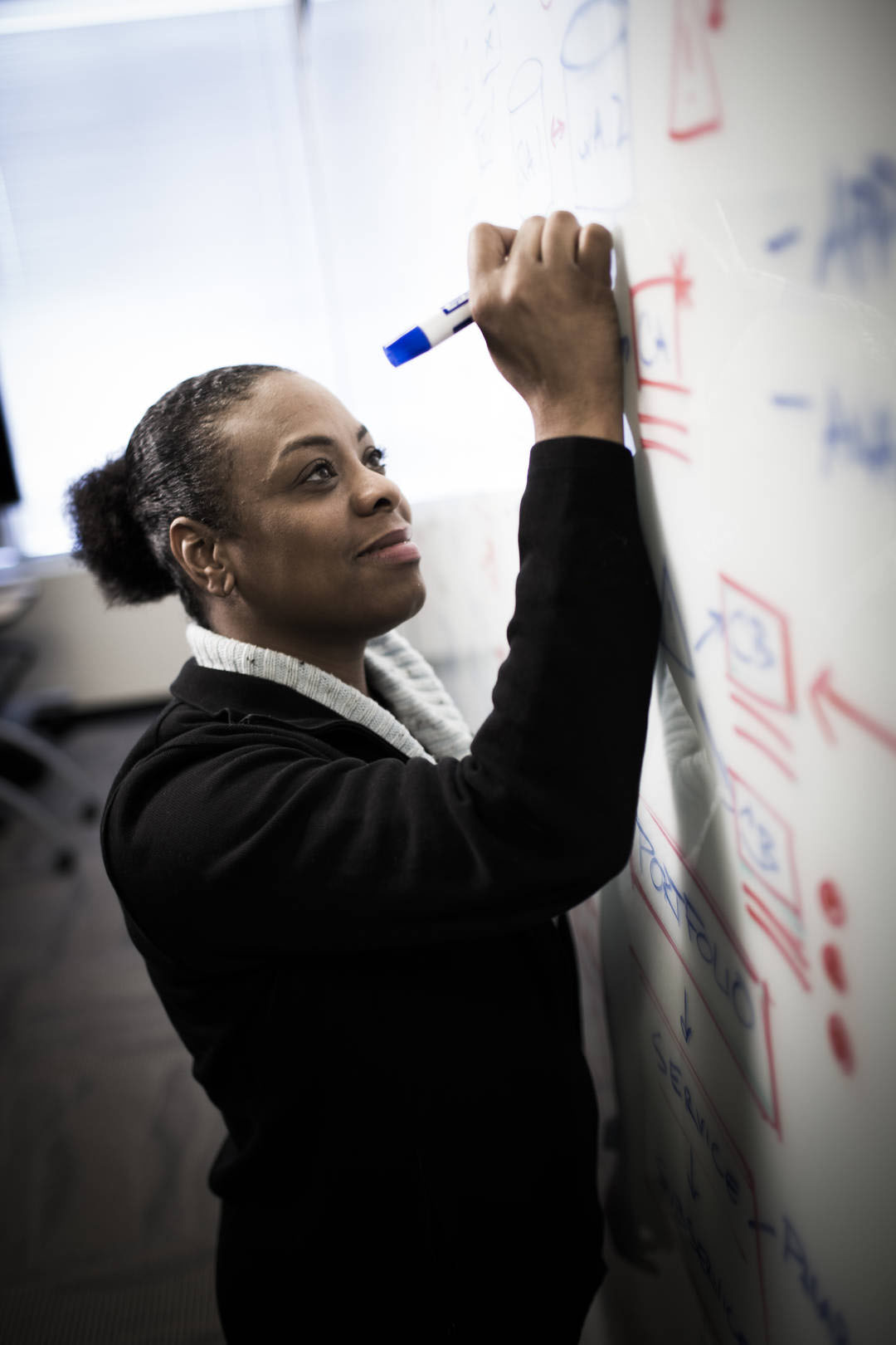 Associate writes on a whiteboard in a meeting